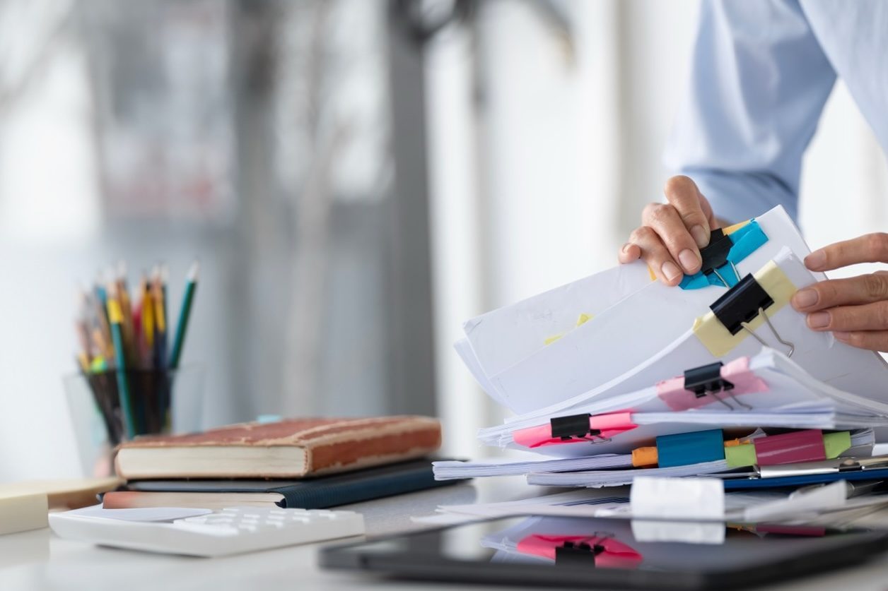 Businesswoman hands working in Stacks of paper files for searching and checking unfinished document achieves on folders papers at busy work desk office Young Woman Bookkeeping
